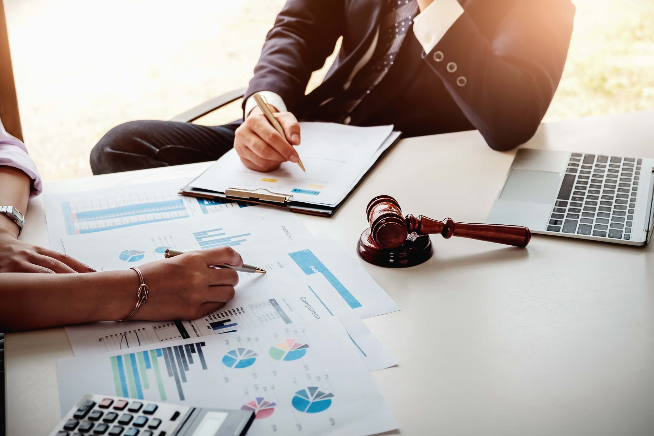 Man and woman discussing analytics document with gavel on table.