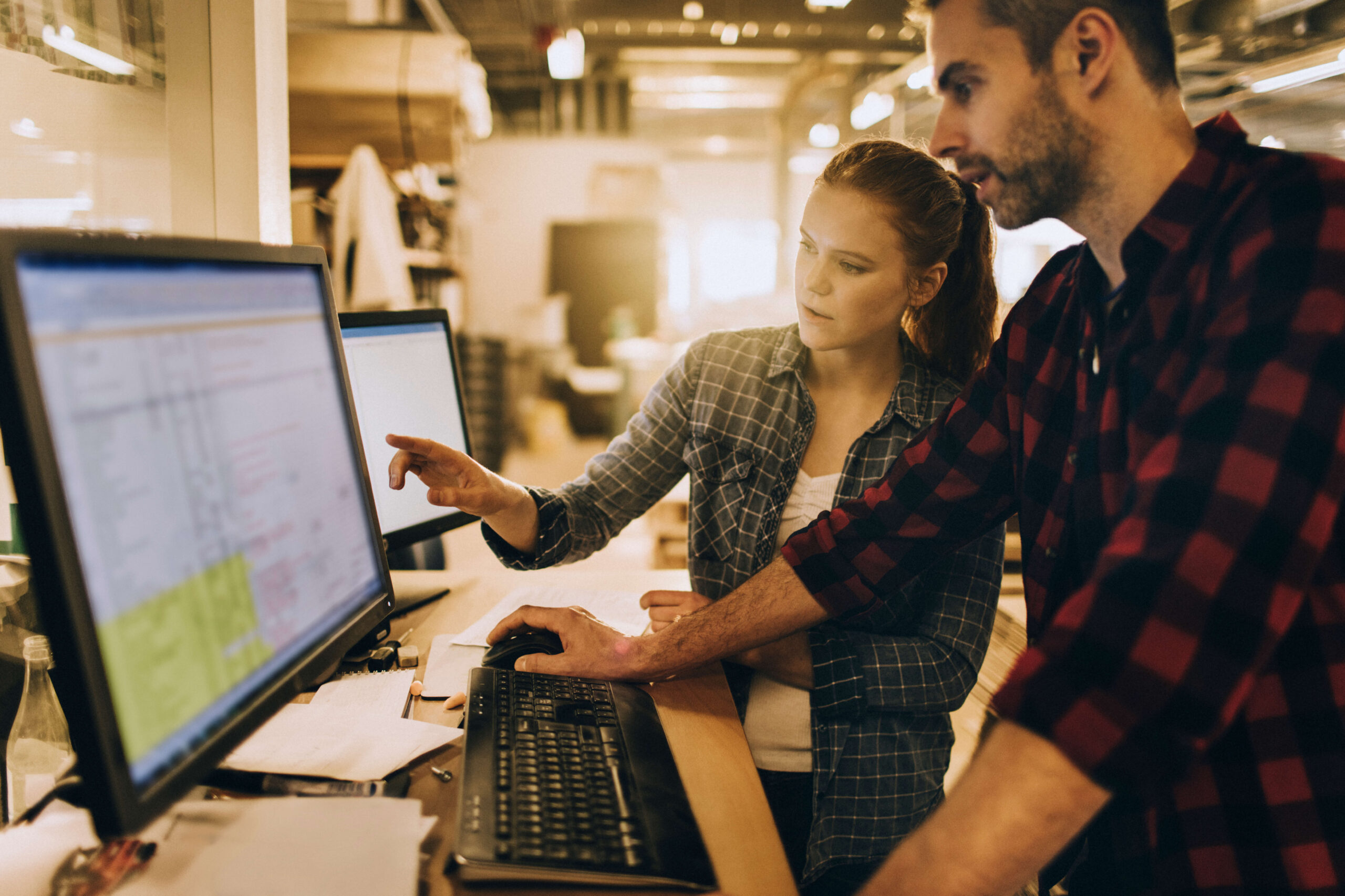 Two team members talking while looking at computer screen.