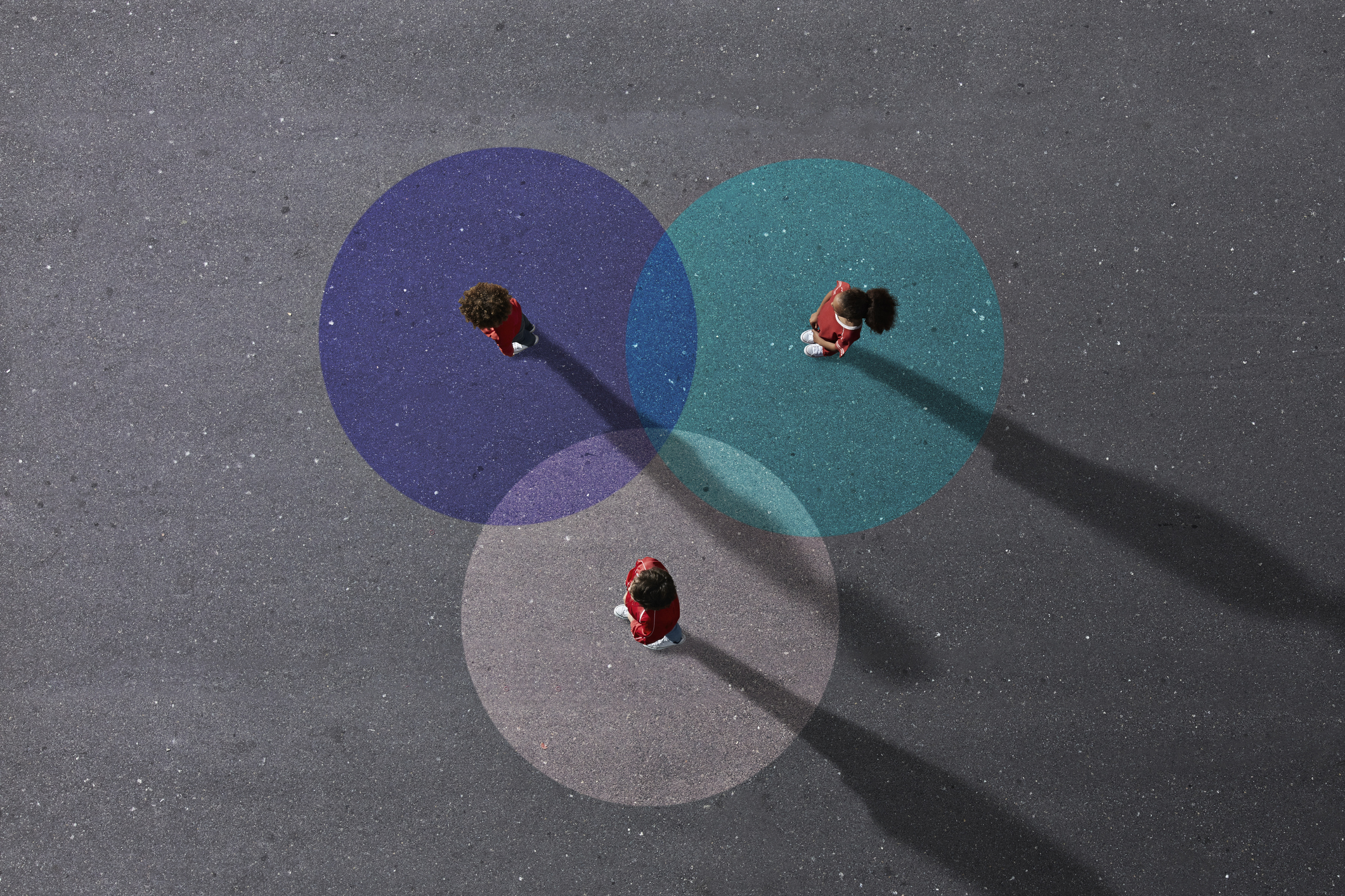 Group of children photographed from above on various painted tarmac surface at sunset
